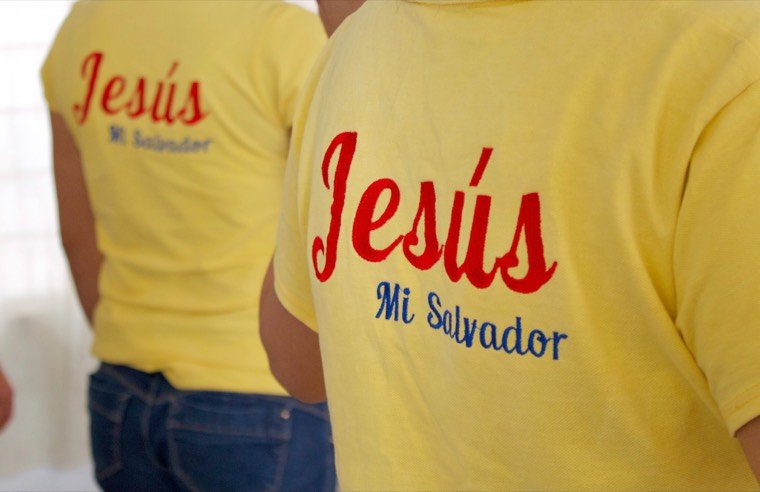 Dos residentes de espaldas con la camisa del refugio, que dice «Jesús Mi Salvador»